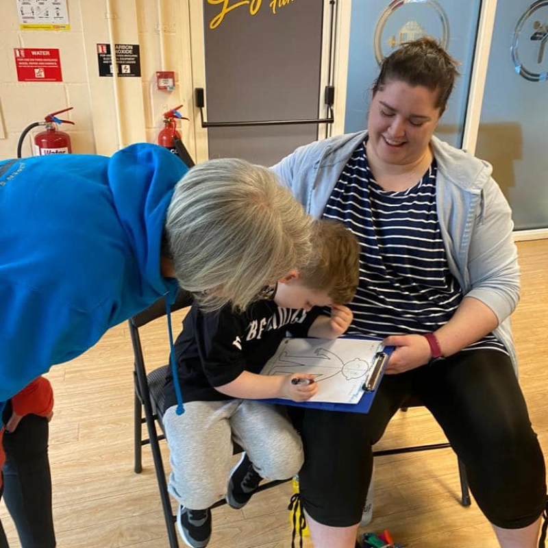 Natalie with parent and child writing on clipboard